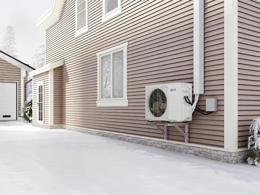 Outdoor mini-split condenser on a wall bracket beside a house in winter snow